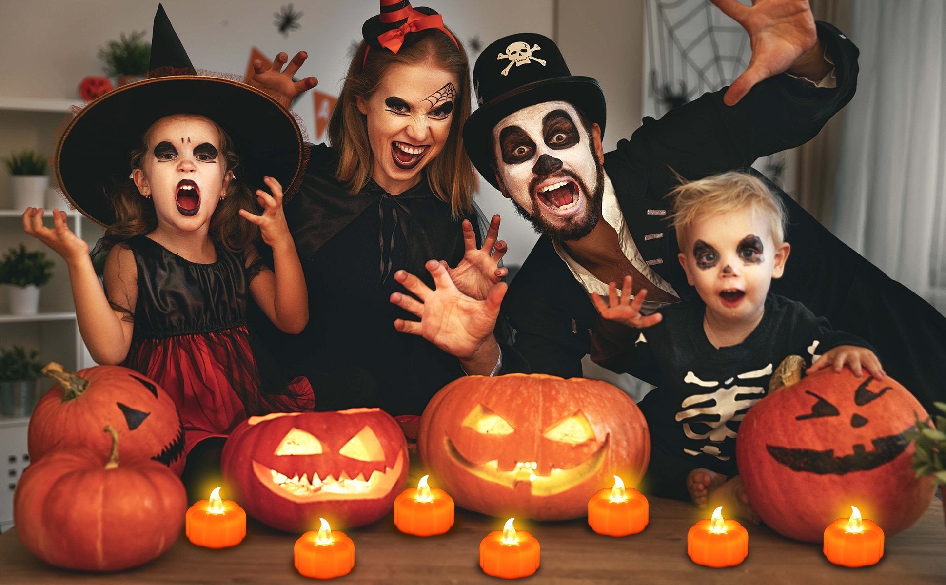 Family in Halloween costumes with carved pumpkins and LED tea lights