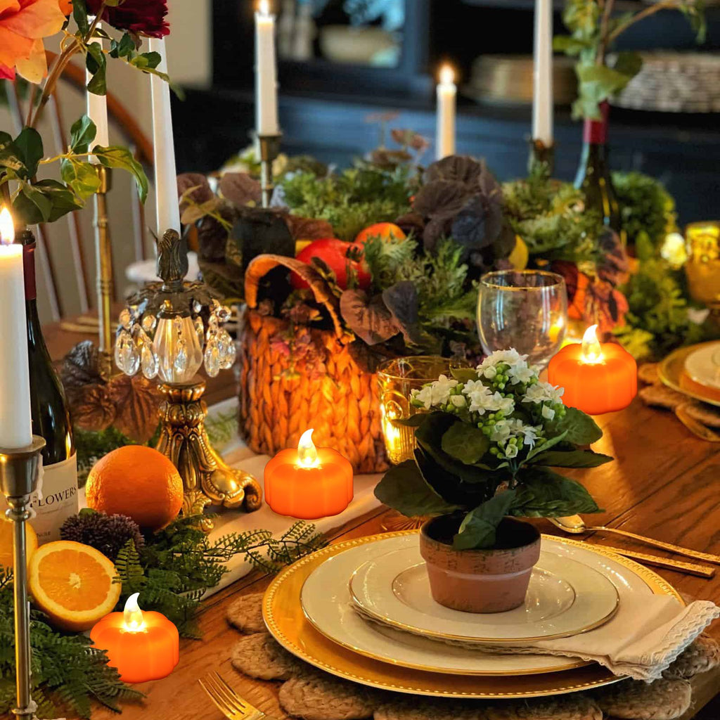 Table setting with orange pumpkin LED tea lights, oranges, and candles for a festive autumn display.