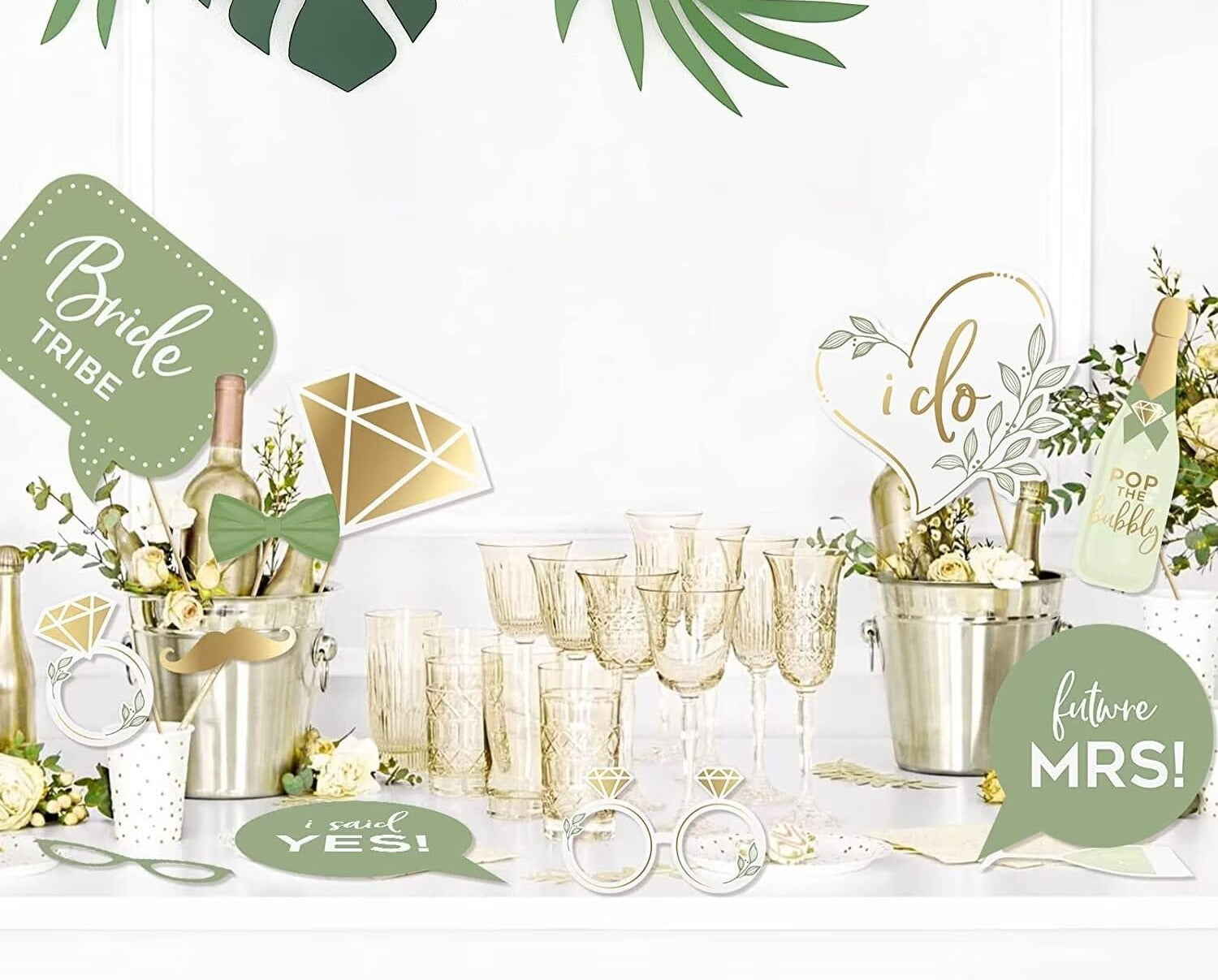 Wedding photo booth props kit with champagne, glasses, and decorative signs like 'Bride Tribe' and 'I Do'.