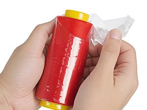 Hands unwrapping a red serger thread cone with yellow ends, on a white background.