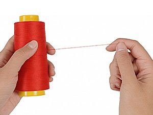 Hands holding a red spool of polyester serger thread, pulling a single strand.