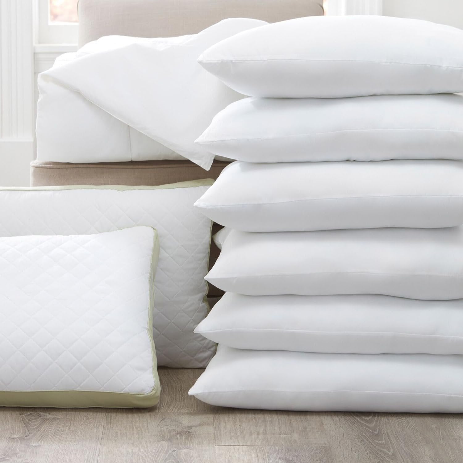 Stack of white microfiber pillowcases with envelope closure and a quilted pillow on a wooden floor.