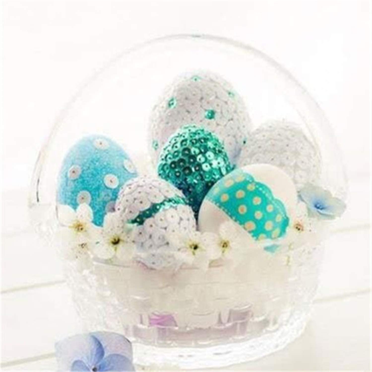 Decorated Easter eggs in a clear basket with white flowers, featuring blue and white polka dots and teal sequins.
