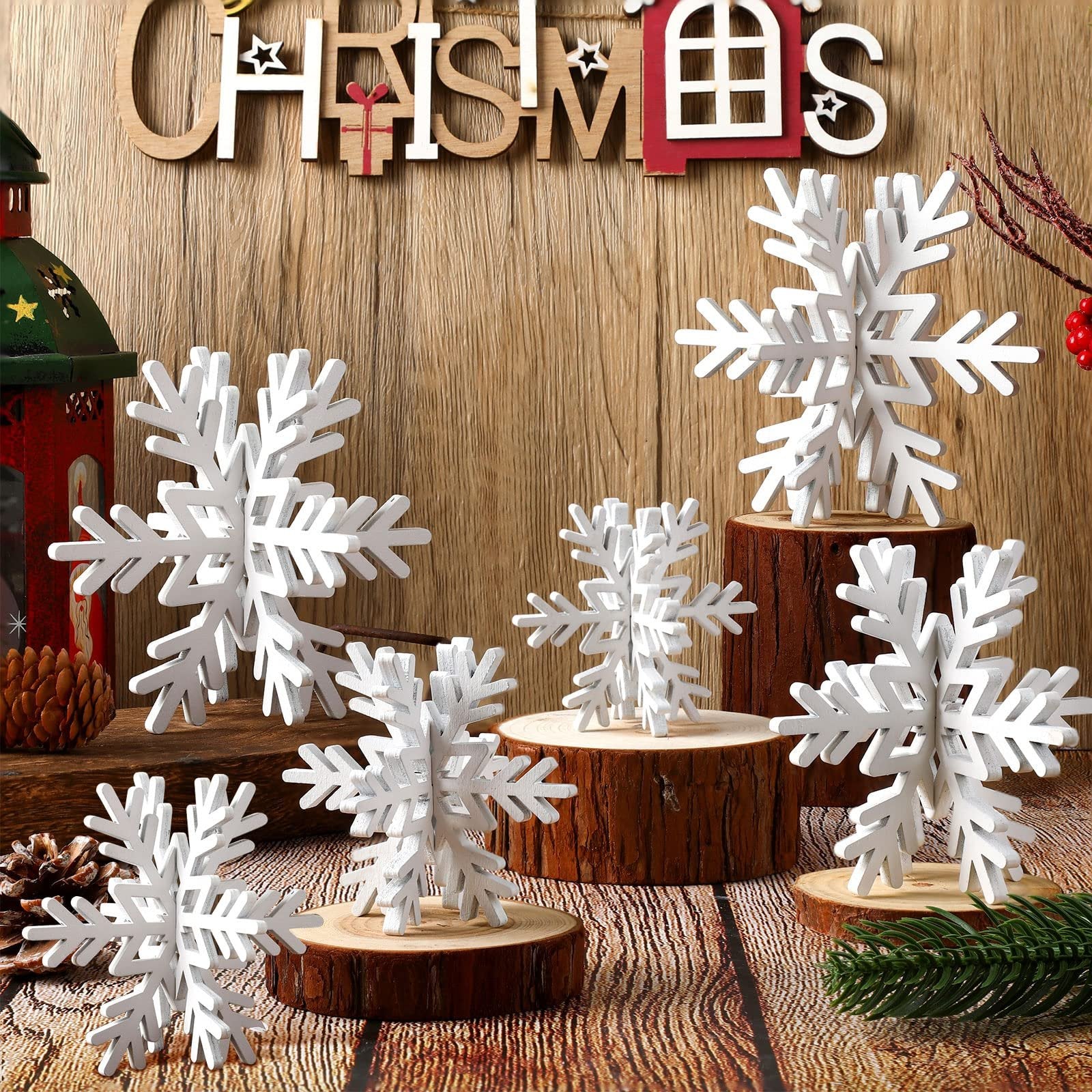 White 3D wooden snowflakes of various sizes displayed on wood slices and logs, with a wooden 'CHRISTMAS' sign above.