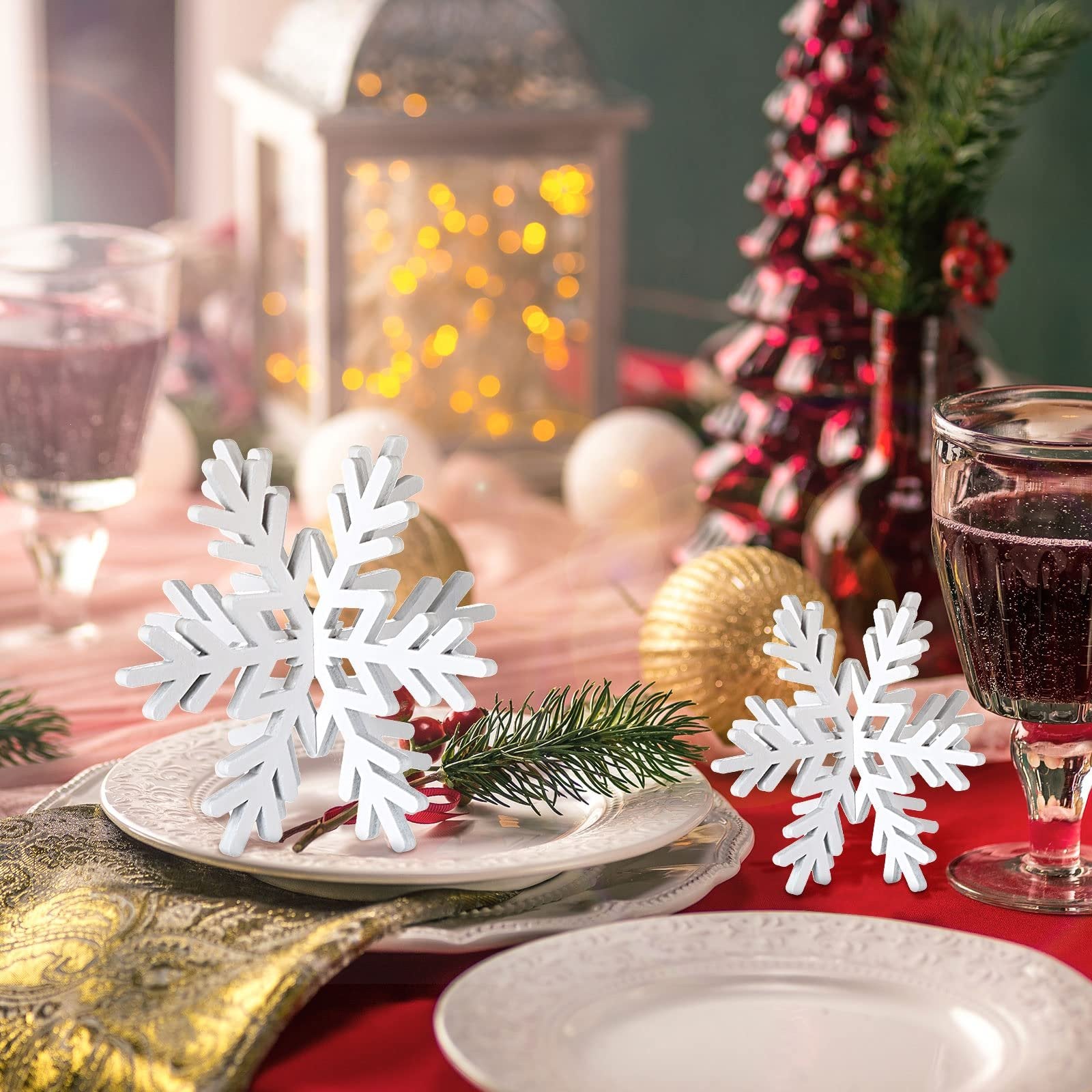 Three white 3D wooden snowflakes on a festive Christmas table setting with plates, glasses, and decorations.