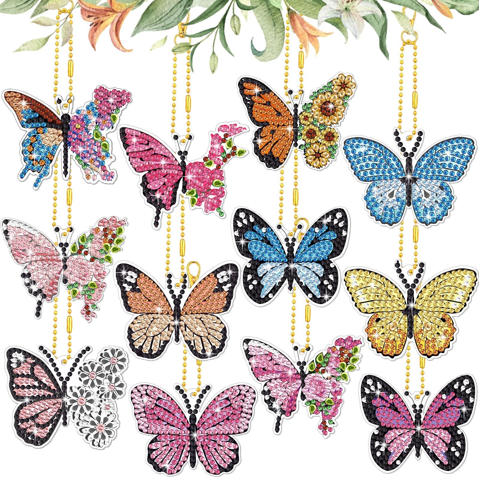 Collection of 12 diamond painting butterfly keychains hanging with gold chains against a floral background.