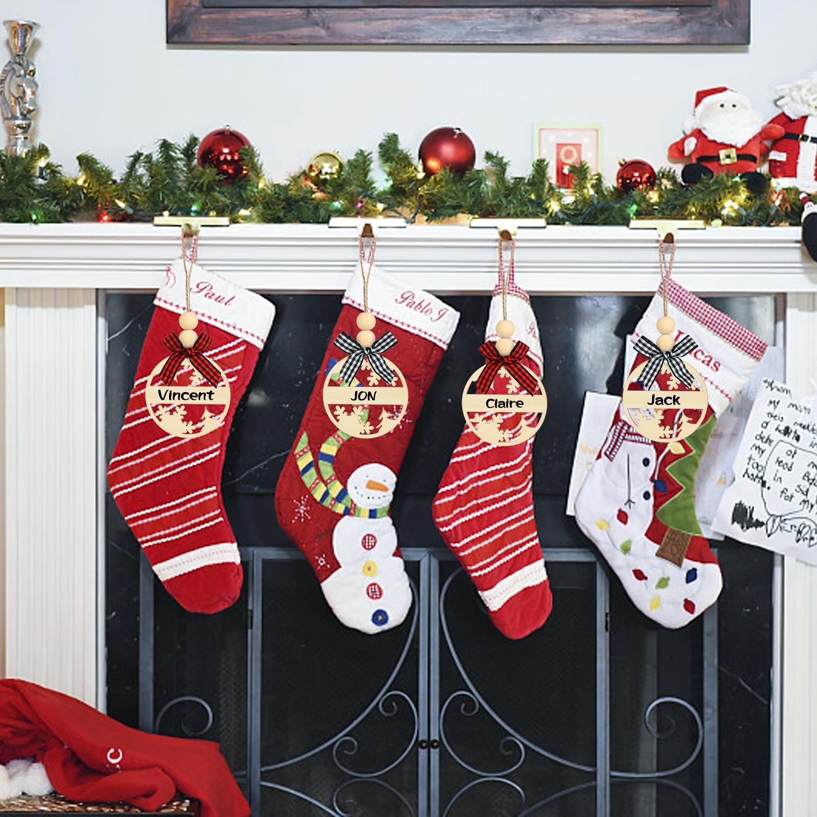 Four Christmas stockings hanging on a fireplace mantel, each with a personalized wooden name tag.