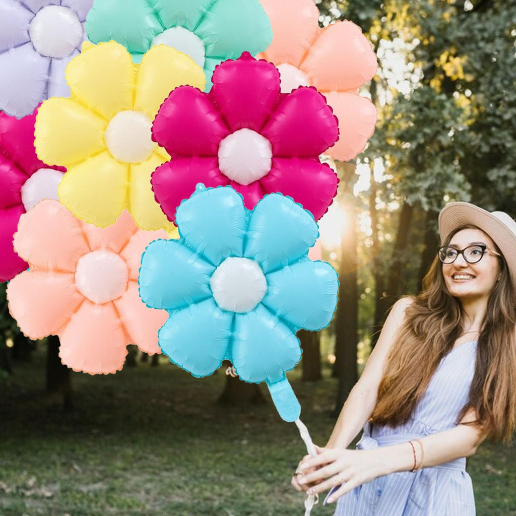 Woman holding a bouquet of colorful daisy-shaped foil balloons outdoors