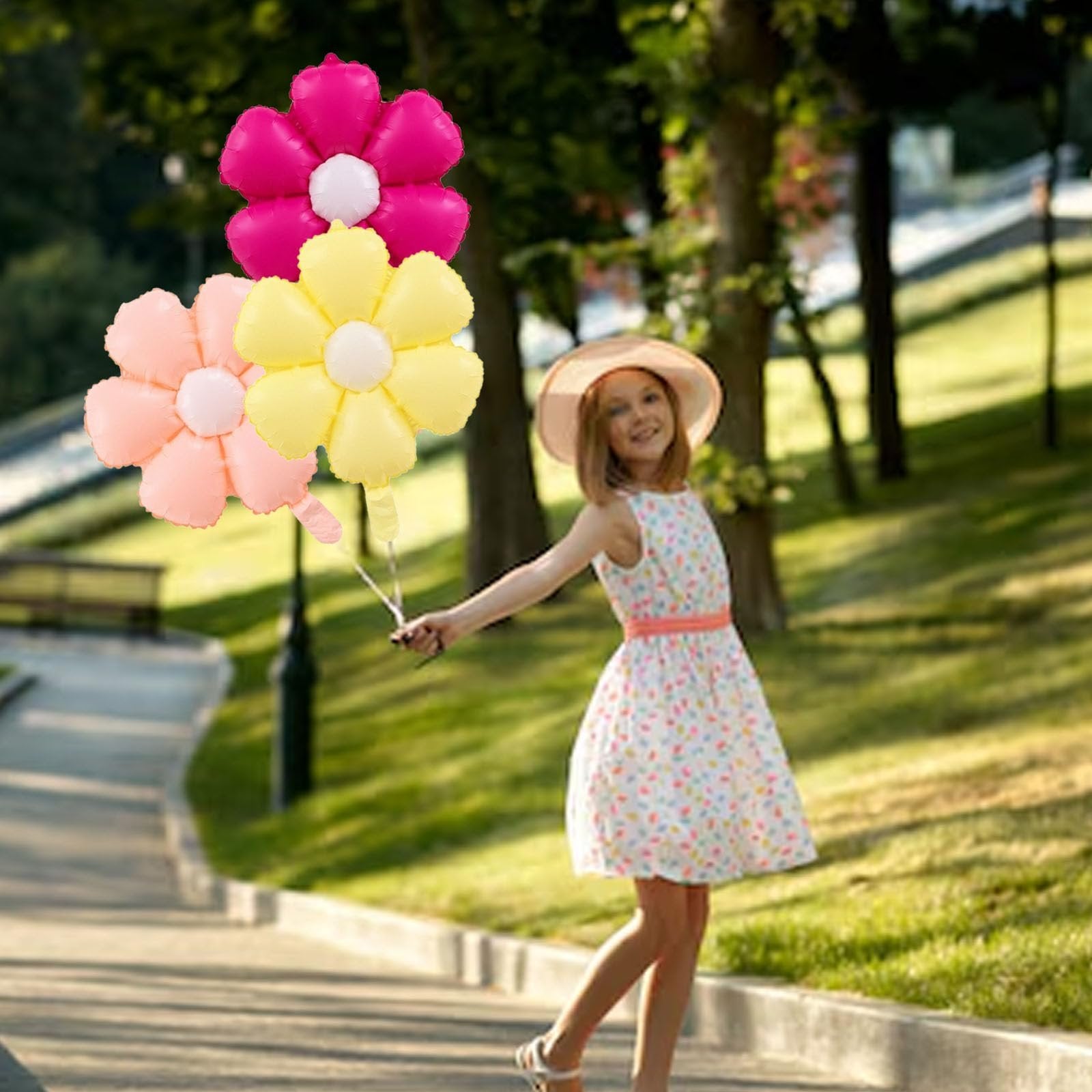 Girl in a floral dress holding pink, yellow, and peach daisy balloons in a park