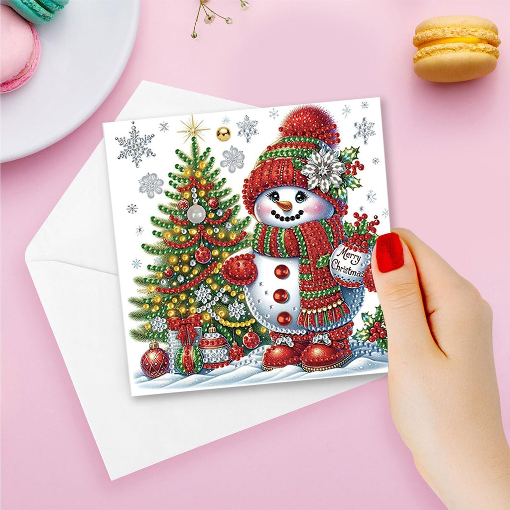 Diamond art painting Christmas card featuring a snowman and decorated tree, held by a hand.