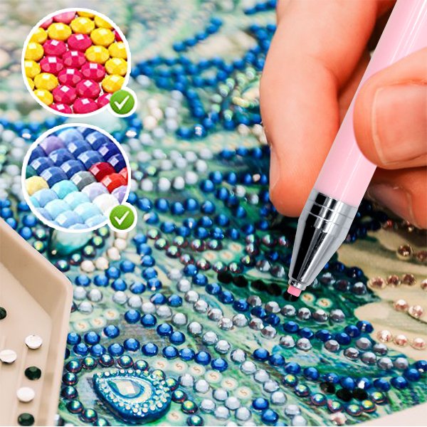 Diamond painting pen applying pink wax to a canvas with blue and silver beads, close-up view