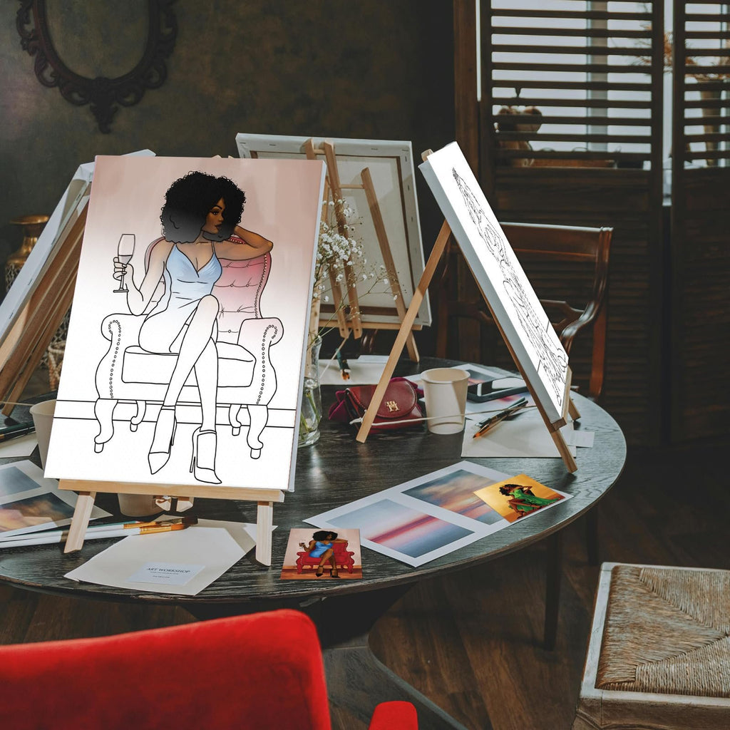Two pre-drawn canvases on easels, one with a colored illustration of a woman with wine, the other a line drawing, on a table with art supplies.