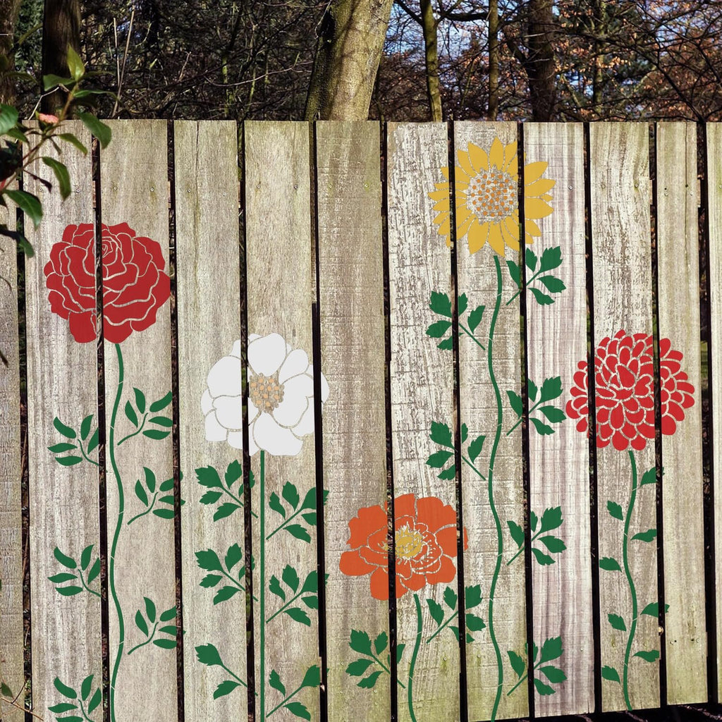 Set of 12 flower stencils applied to a wooden fence, featuring red, white, yellow, and orange floral designs with green stems and leaves.