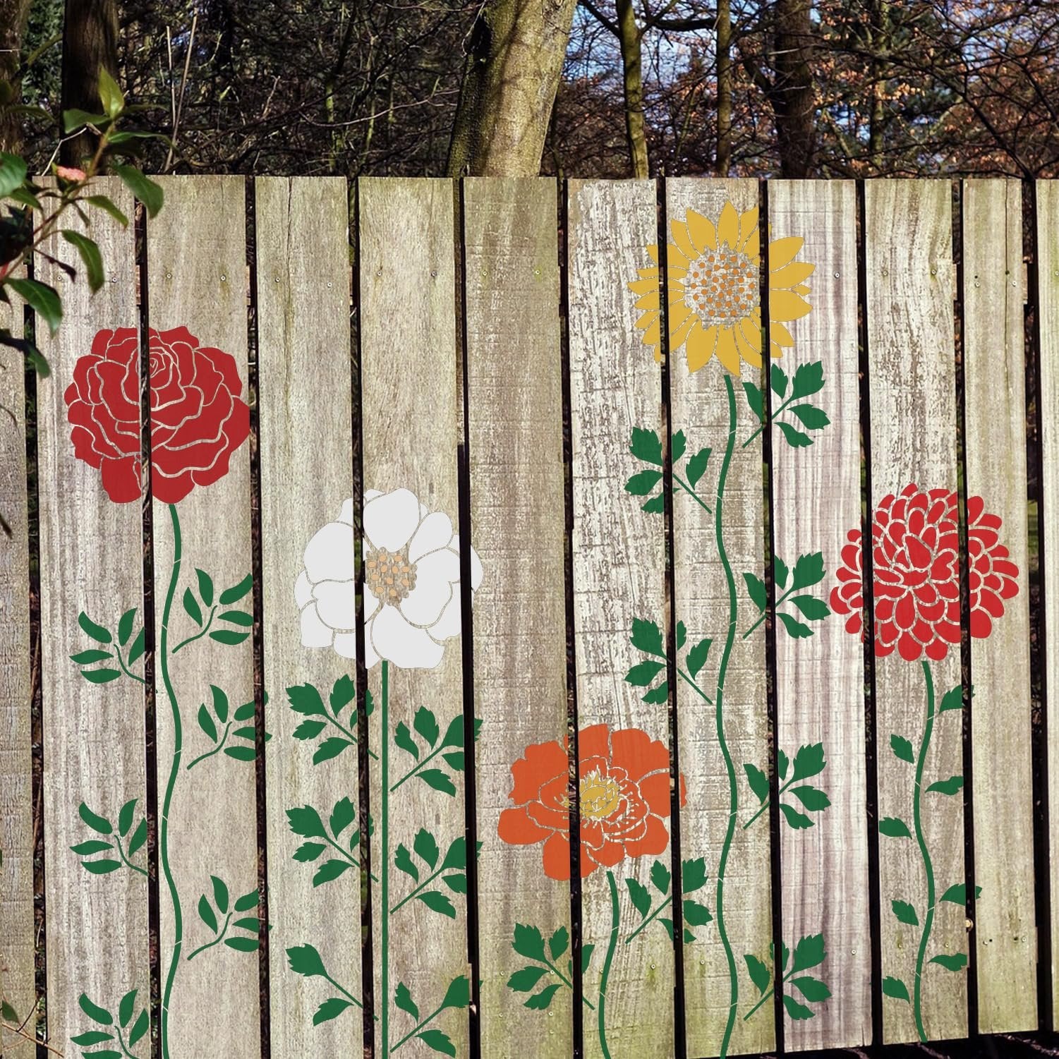 Set of 12 flower stencils applied to a wooden fence, featuring red, white, yellow, and orange floral designs with green stems and leaves.