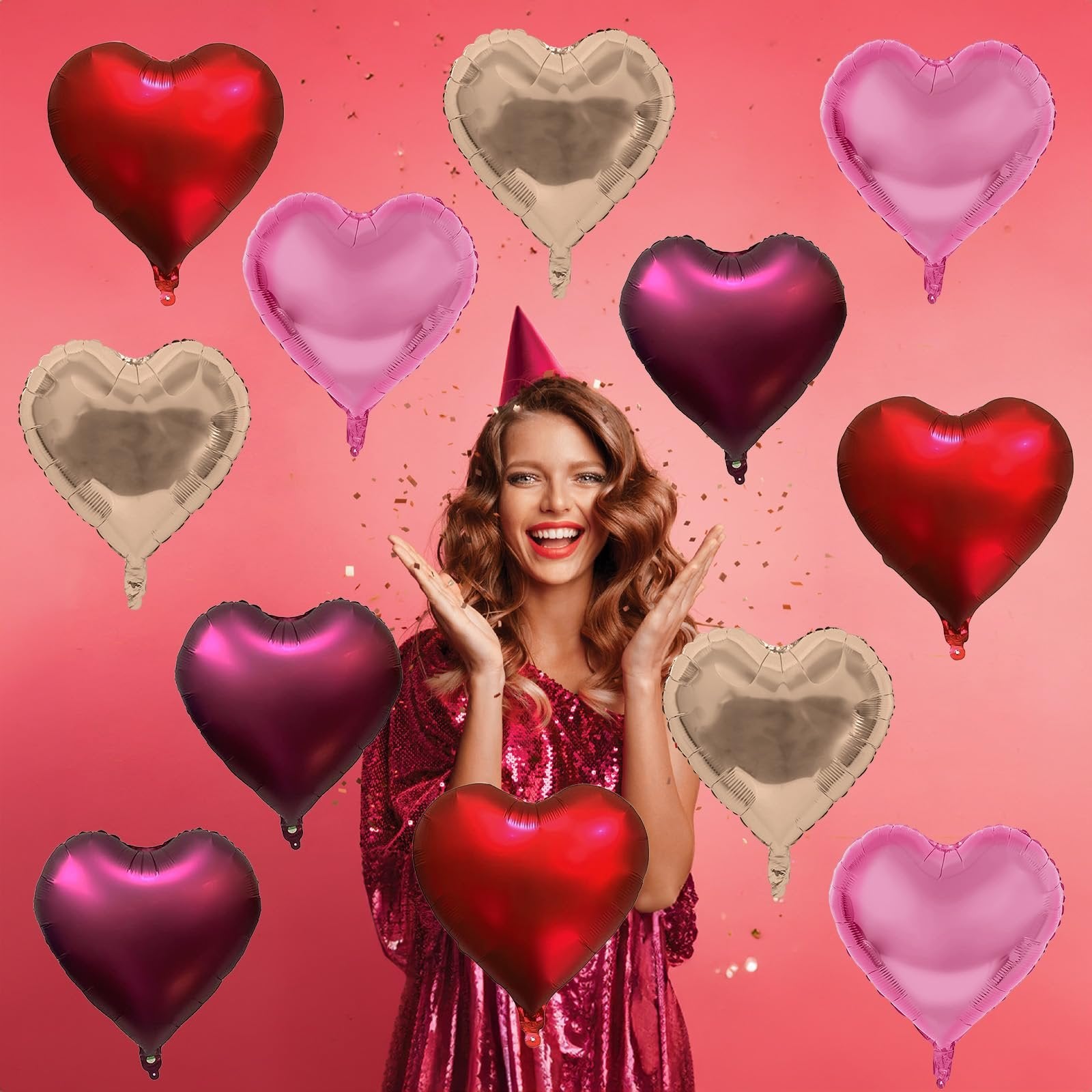 Woman in sequined dress with party hat surrounded by assorted heart-shaped foil balloons