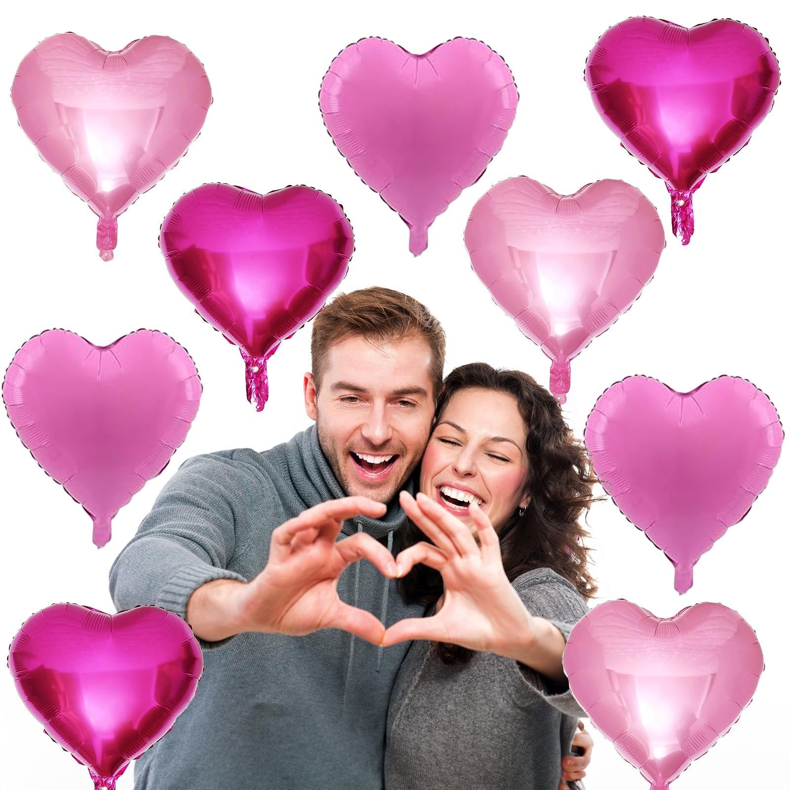 Couple making a heart shape with hands surrounded by pink heart-shaped foil balloons