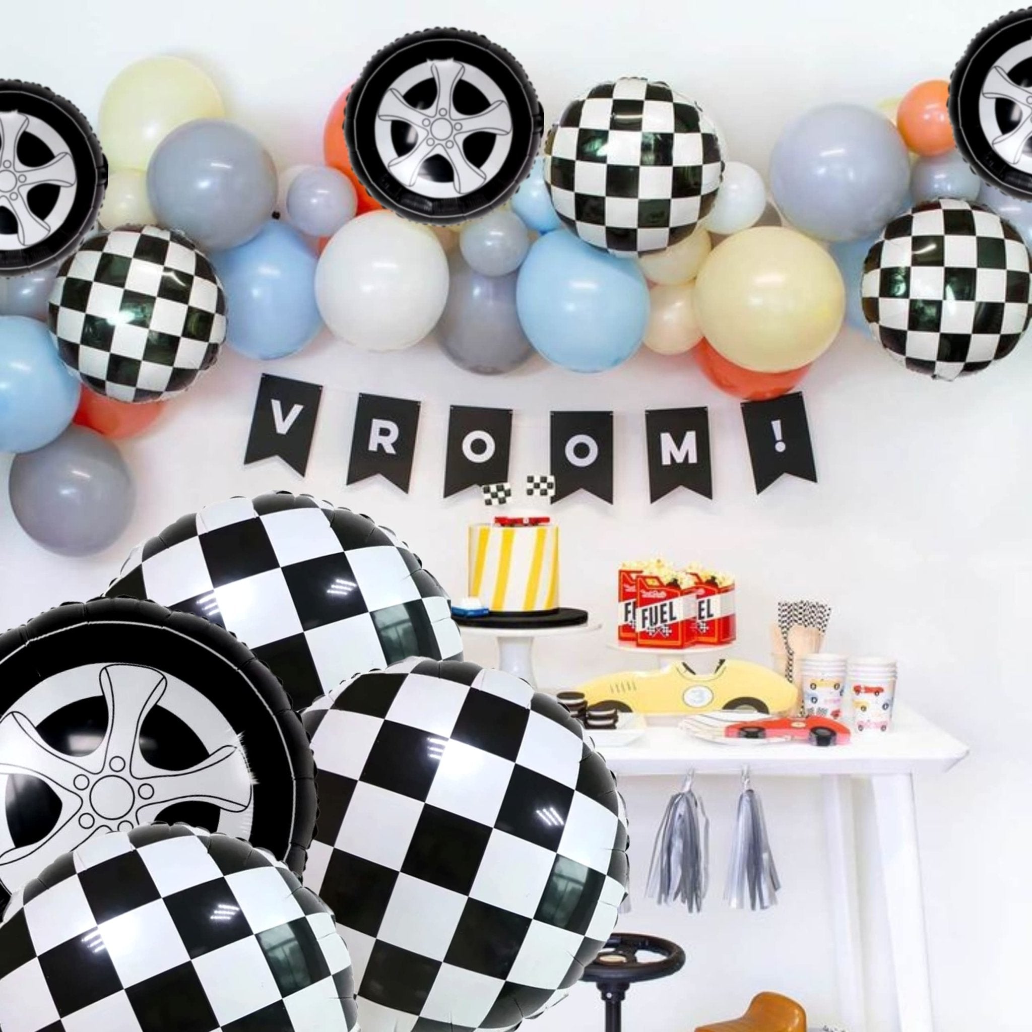Race car themed party setup with checkered and wheel balloons, cake, and decorations
