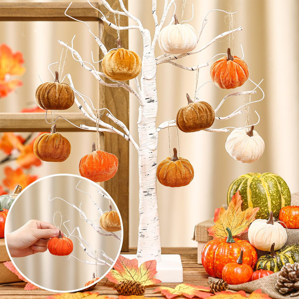 Velvet pumpkins hanging from a white decorative tree, with a close-up inset of a hand holding a pumpkin.