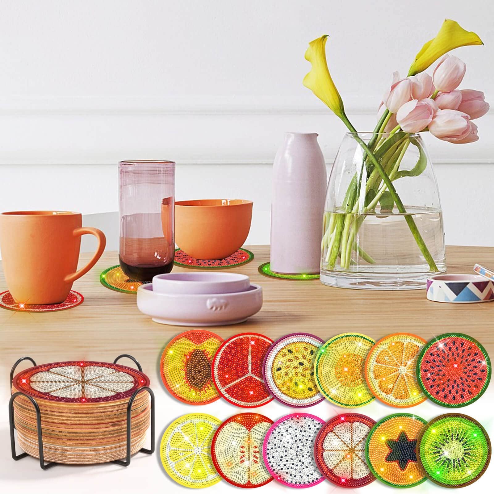 Diamond art coaster kit with fruit designs and holder, displayed with mugs and flowers on a table.