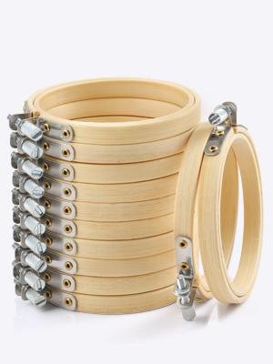Stack of 12 round wooden embroidery hoops with brass screws, one hoop angled in front