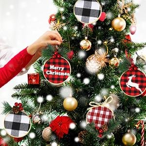 Person decorating a Christmas tree with buffalo plaid round ornaments, one says Merry Christmas