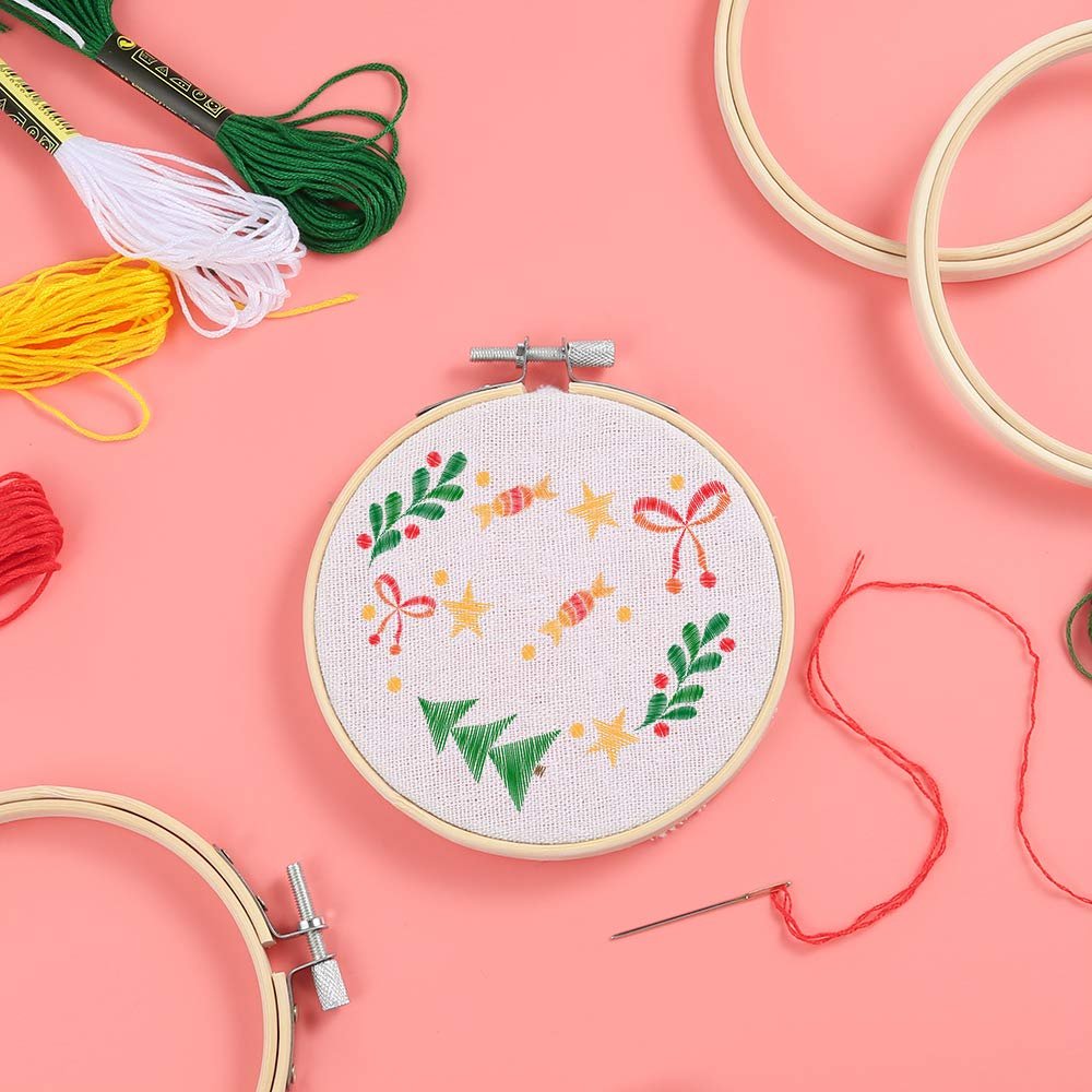 Embroidery hoop with Christmas design, surrounded by embroidery floss and other hoops.