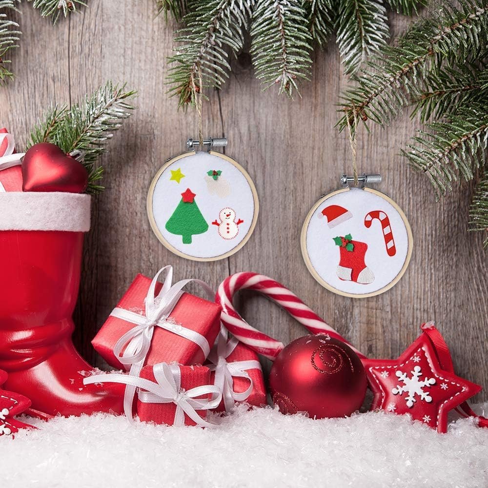 Two Christmas-themed felt embroidery hoop ornaments hanging on a wooden background with festive decorations
