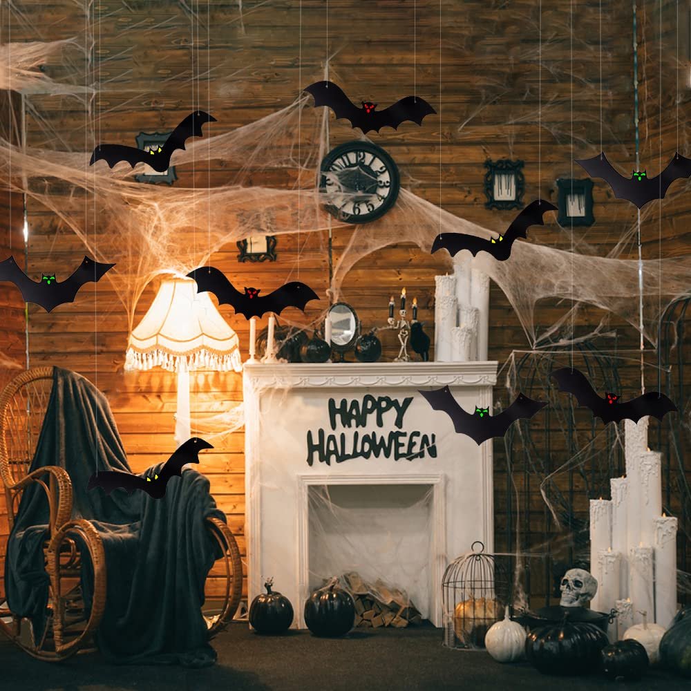 Halloween scene with hanging bat decorations and glowing eyes above a fireplace with 'Happy Halloween' text.