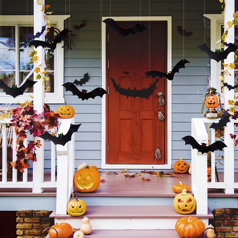 Halloween porch decorated with hanging bats and carved pumpkins, featuring a red door and blue siding.