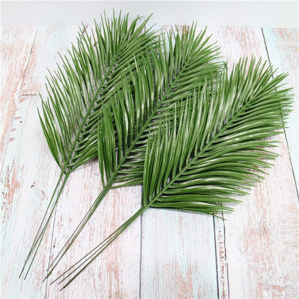 Three artificial palm leaves fanned out on a light wood-grain background.