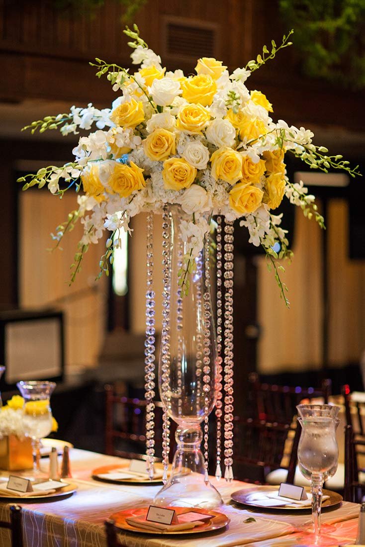 Tall floral centerpiece with yellow and white roses and cascading crystal beads on a table setting.