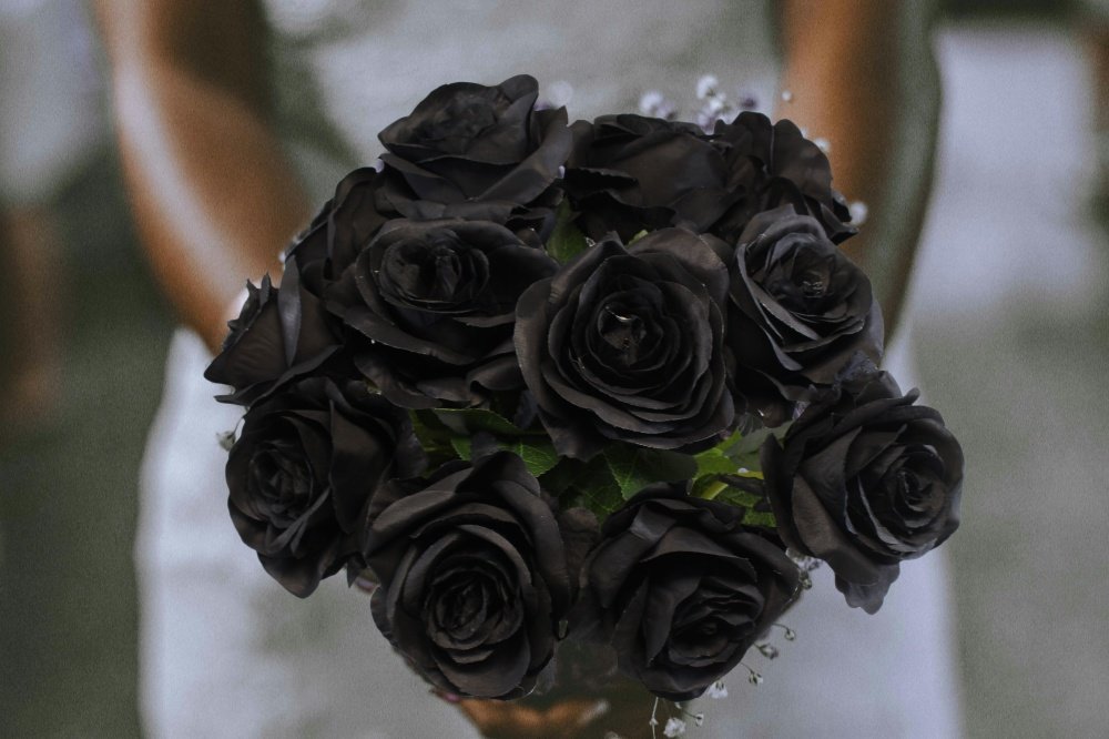 Bouquet of 12 black artificial roses held by a person in a white dress
