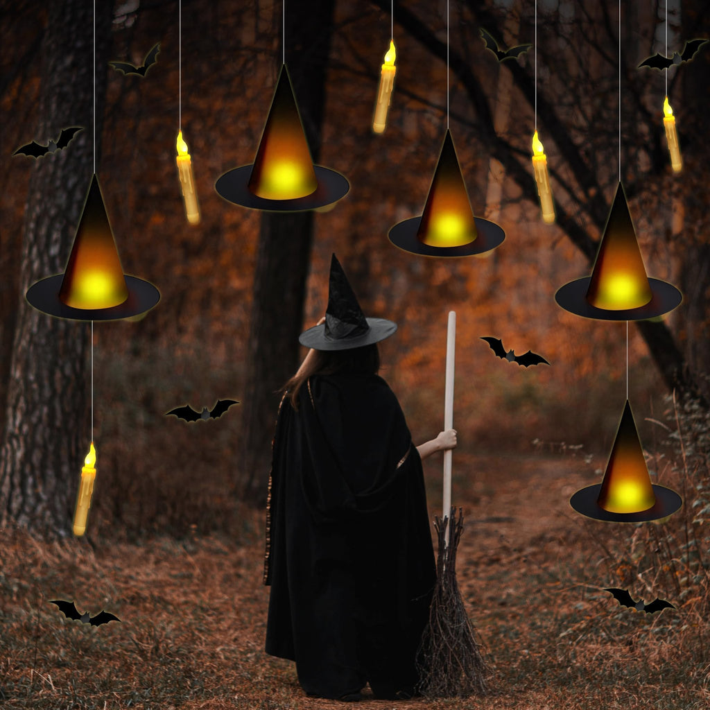 Halloween scene with a person in a witch costume holding a broomstick, surrounded by hanging witch hats and flameless candles.