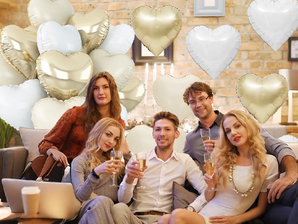 Group of people celebrating with cream white and gold heart balloons