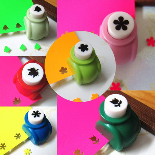 Assorted mini craft hole punches in green, pink, red, blue, and dark green, punching shapes into colored paper.