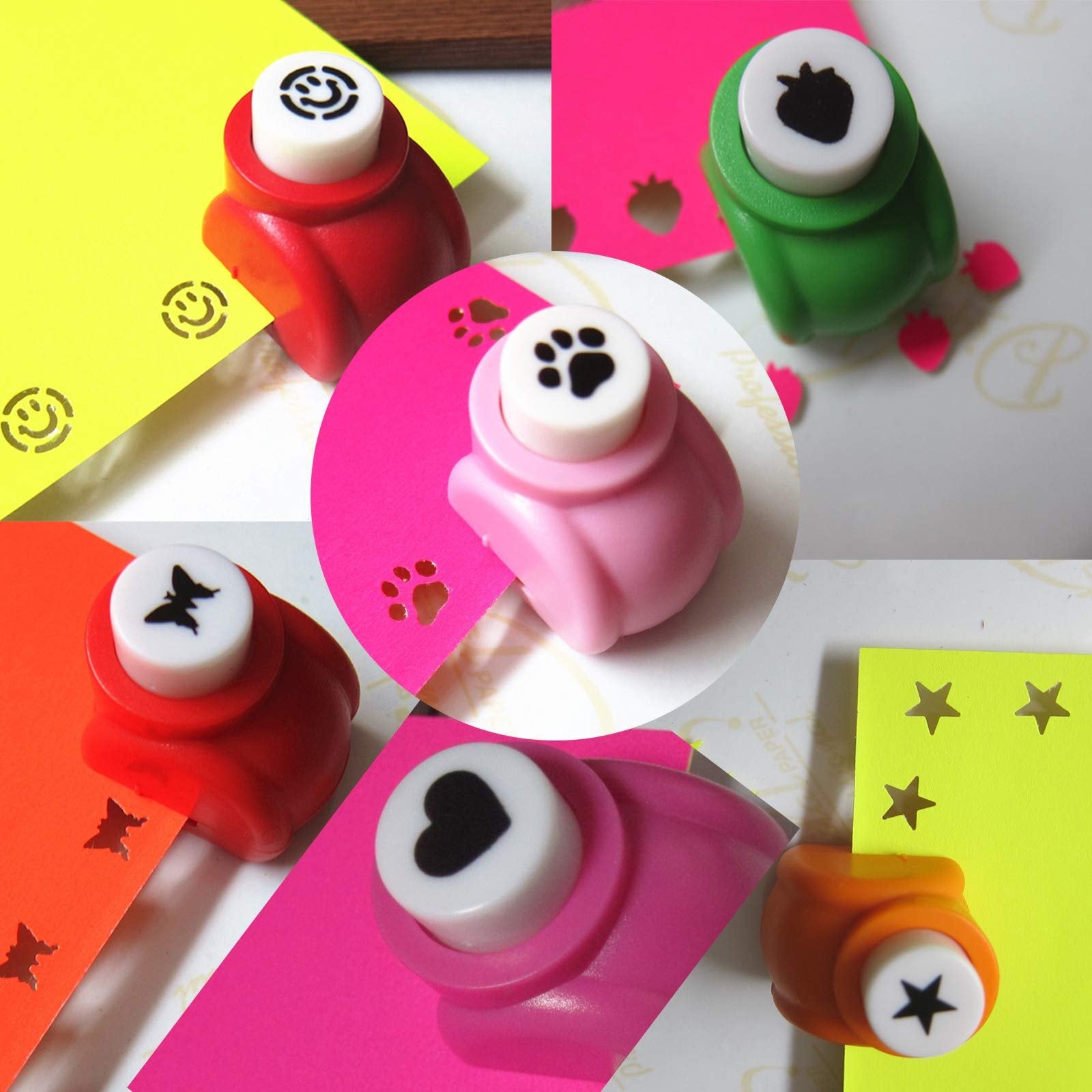 Assorted mini craft hole punches in red, pink, green, and orange, punching shapes into colored paper.