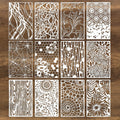 Twelve white stencils with intricate cut-out designs including spider webs, flowers, wood grain, and geometric patterns, arranged in a 3x4 grid on a brown wooden background.