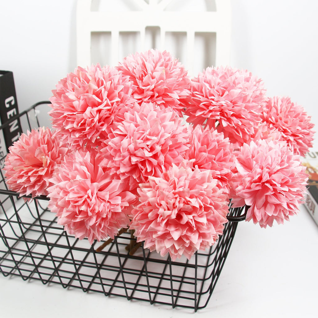 Bouquet of pink artificial chrysanthemum flowers in a black wire basket, close-up view