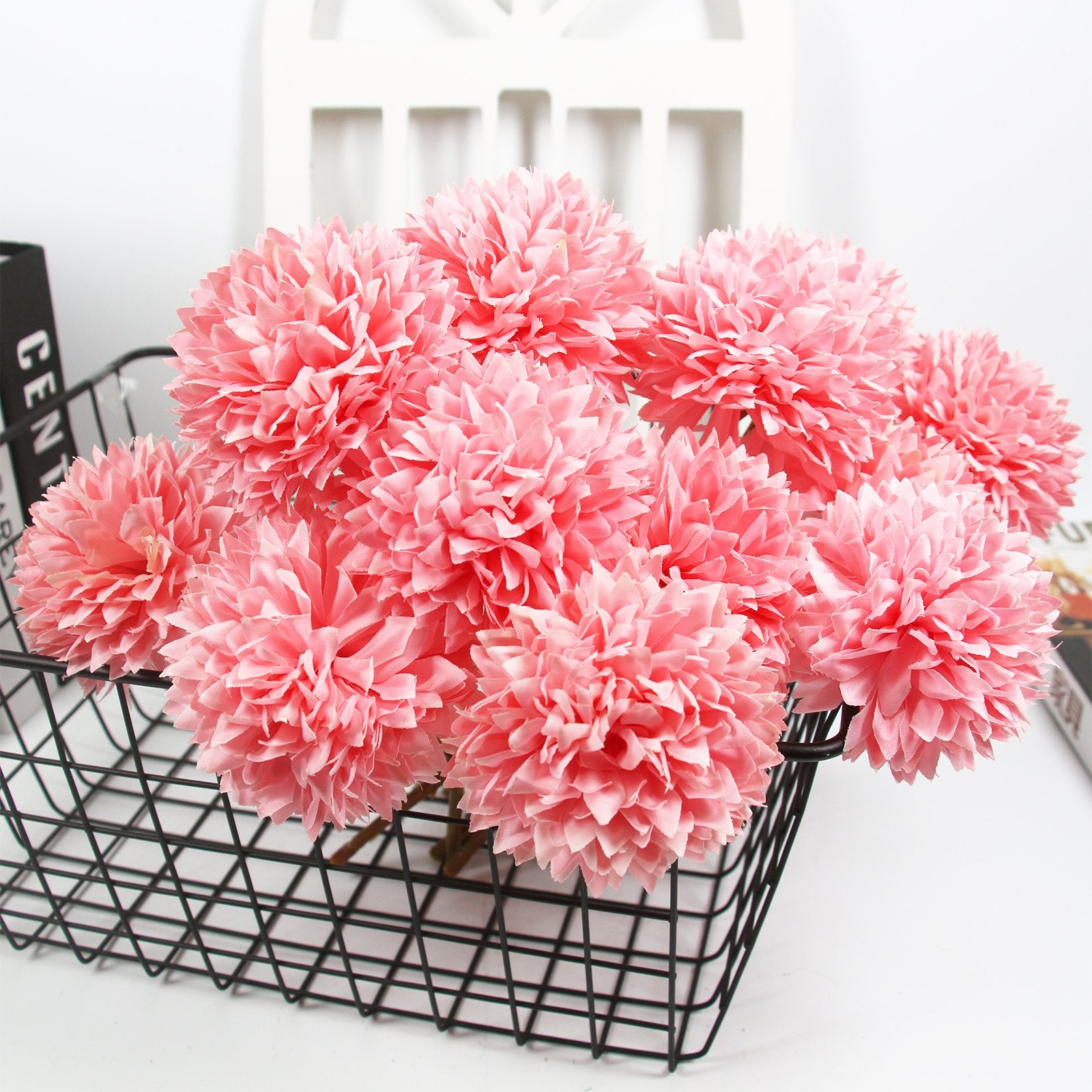 Bouquet of pink artificial chrysanthemum flowers in a black wire basket, close-up view