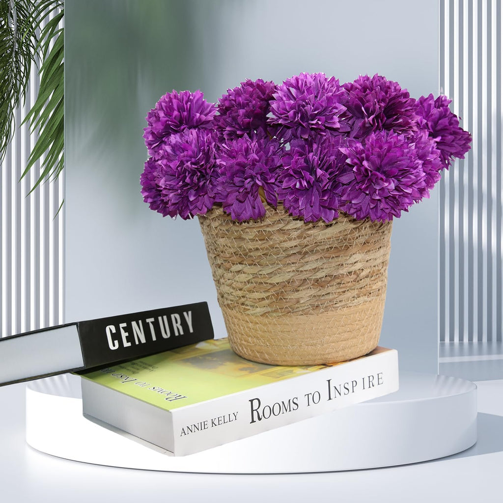 Bouquet of 12 purple artificial chrysanthemum flowers in a woven basket on top of books.