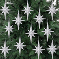 Twelve silver glitter Bethlehem star ornaments hanging on a green Christmas tree