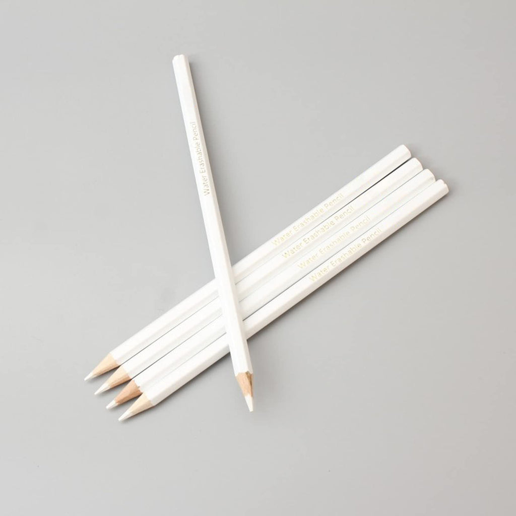 Several white water-soluble marking pencils arranged diagonally on a gray background, with text printed on their sides.