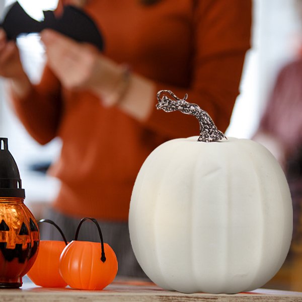 White foam pumpkin with glittery stem on a table with Halloween decorations