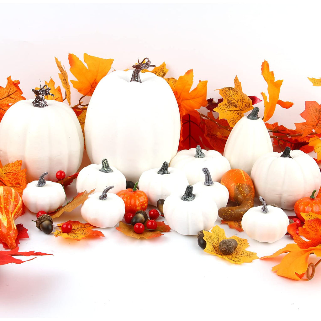 Assorted white foam pumpkins and fall decor including leaves and acorns on a white background.