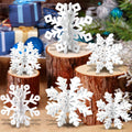 White wooden 3D snowflakes displayed on wood slices with a festive holiday background of gifts and greenery.
