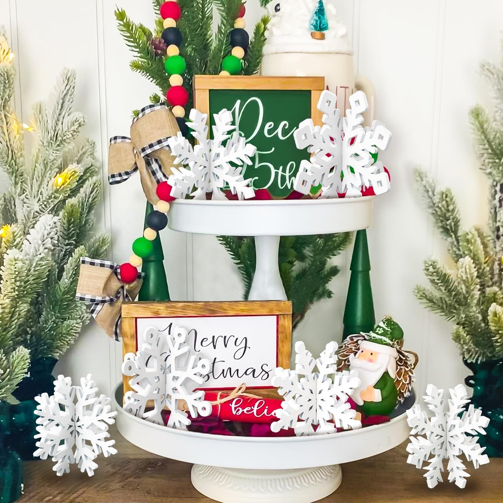 Tiered tray decorated with white wooden snowflakes, festive signs, and Christmas figurines.