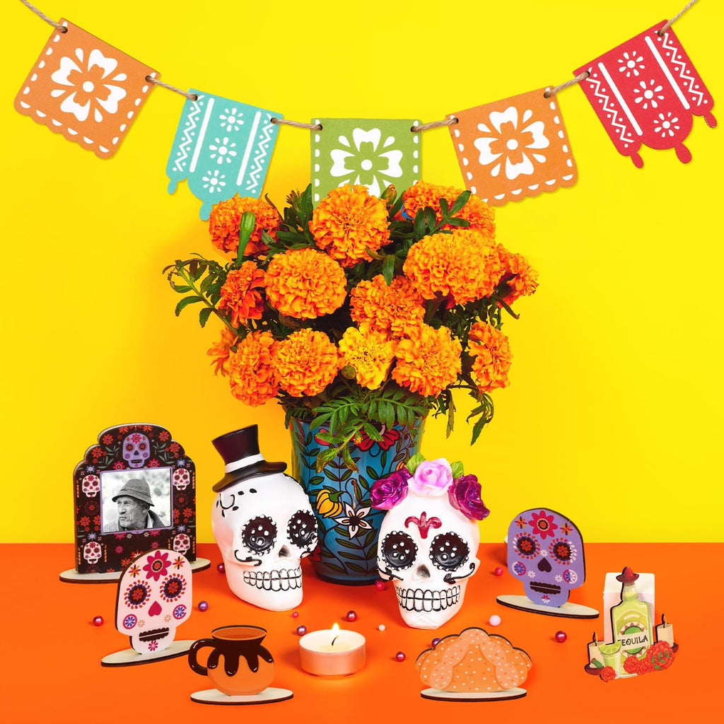 Dia de los Muertos tiered tray decor set with skulls, banners, and marigolds on a yellow background.