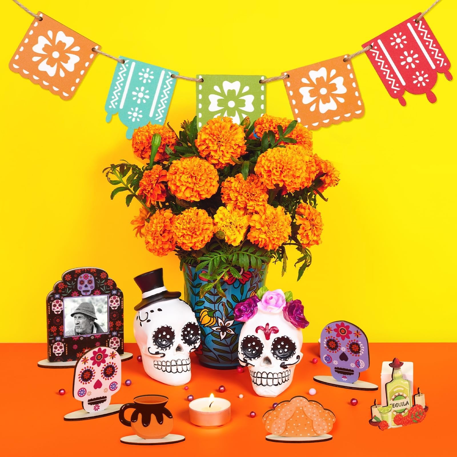 Dia de los Muertos tiered tray decor set with skulls, banners, and marigolds on a yellow background.