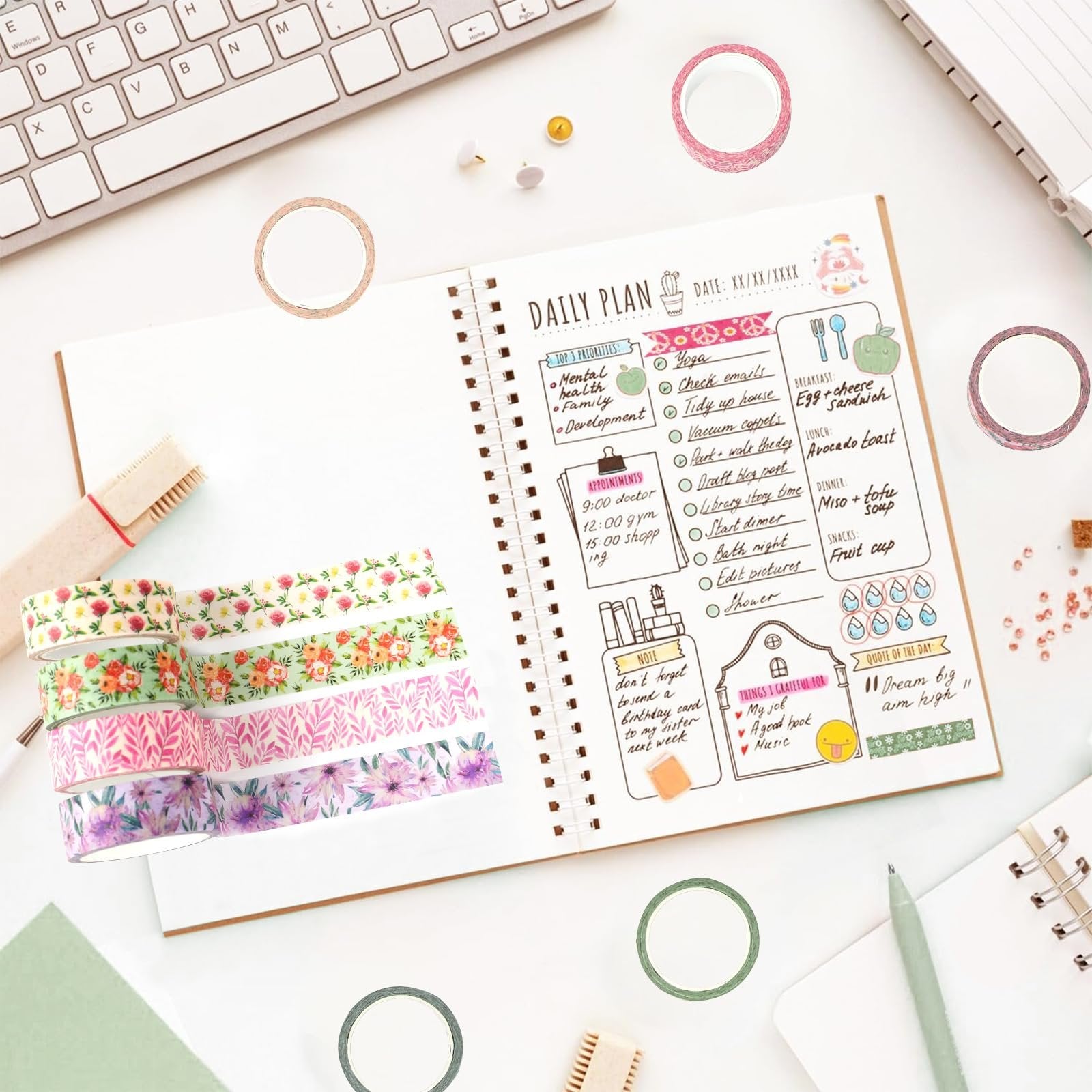 Stack of floral washi tape rolls next to an open daily planner on a desk with a keyboard.