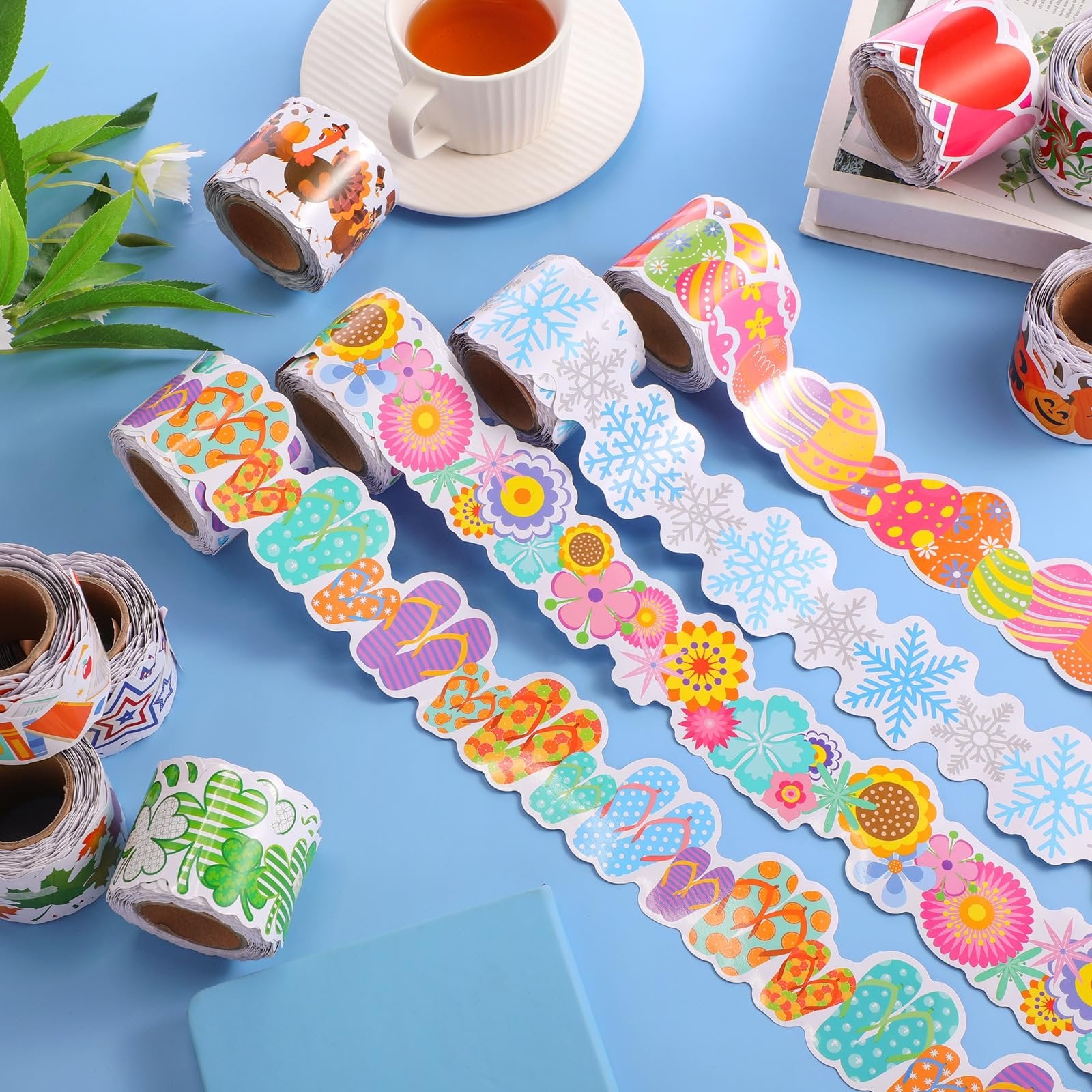Assortment of decorative bulletin board border rolls with various seasonal designs like flip-flops, flowers, snowflakes, and Easter eggs.